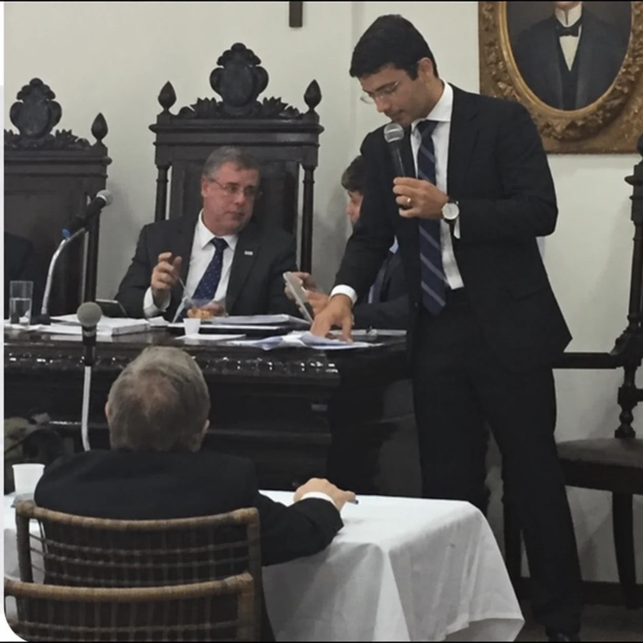 Harrison Leite ao microfone diante da mesa de uma sessão solene.