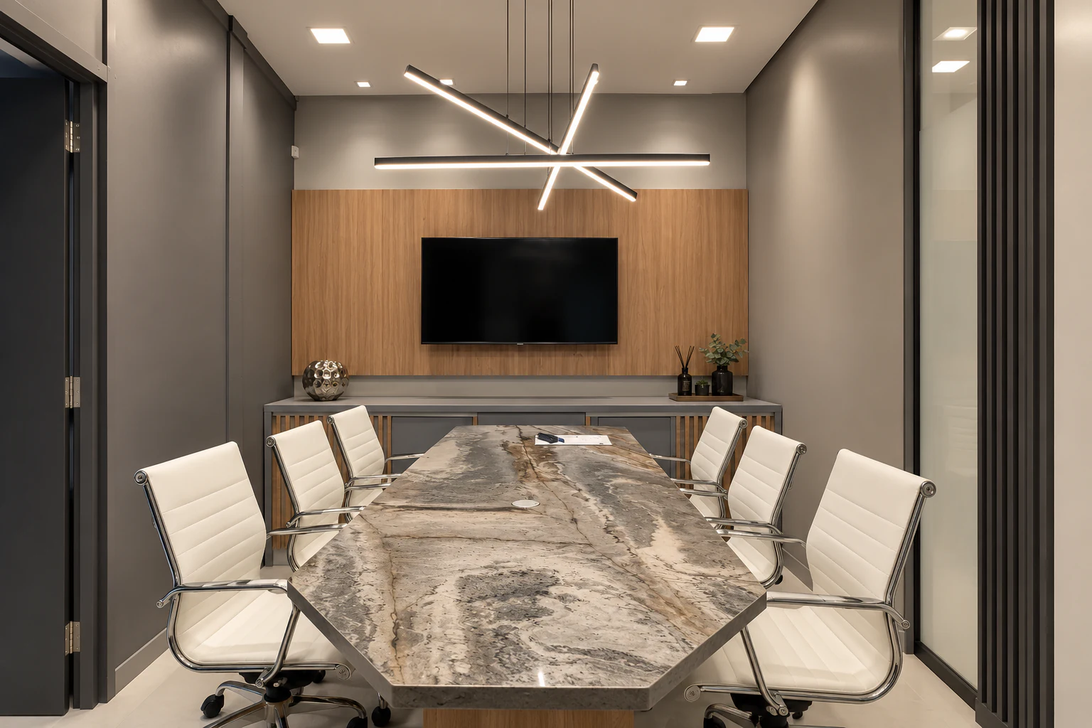 Sala de reuniões da unidade de Vitória da Conquista, com mesa de pedra natural e luminária linear.
